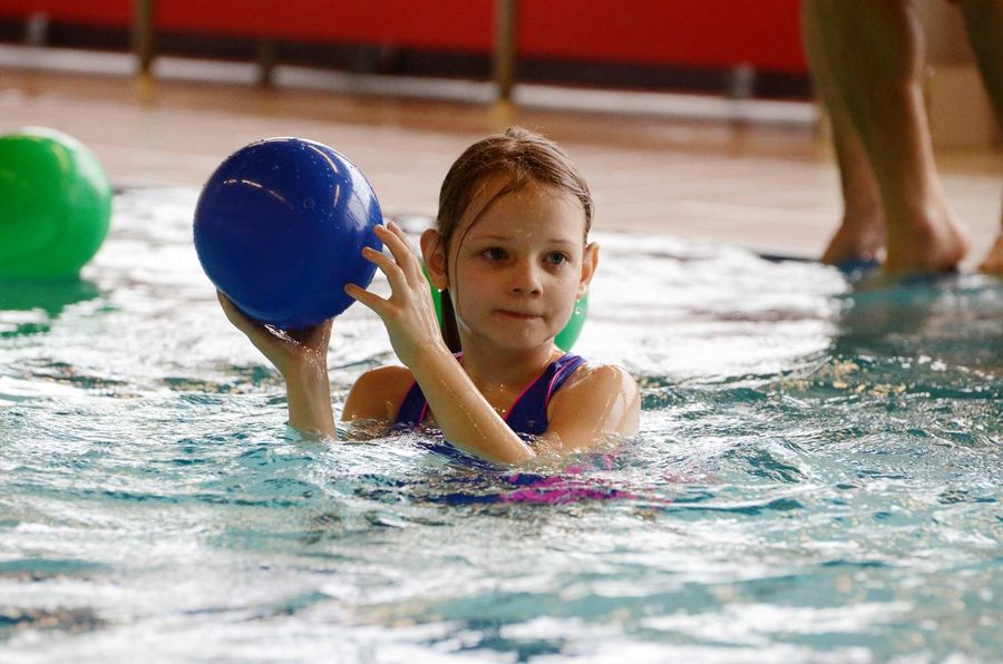 Mädchen spielt mit einem Ball im Wasser